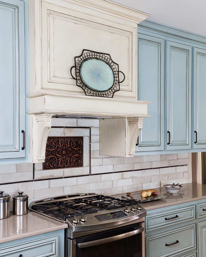 stove top, light blue cabinets, off-white subway tile backsplash