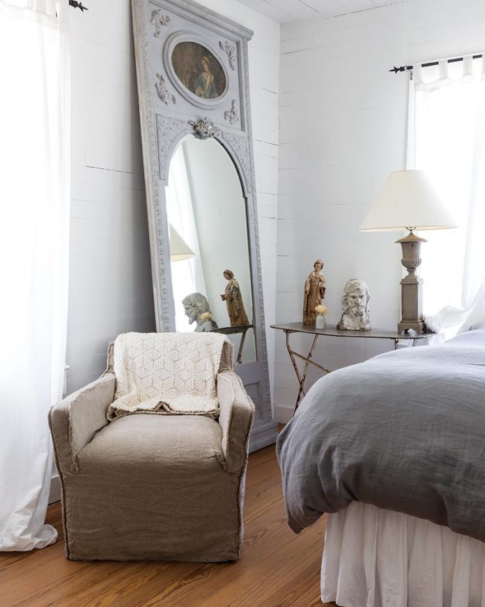neutral bedroom with vintage mirror propped against wall