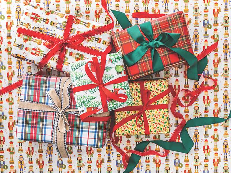 Presents wrapped in plaid, nutcracker, and Christmas tree gift wrap. 