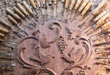 This Minnesota Wood-Carver’s Custom Creations Bring Warmth and Character to Homes A set of chisels surrounding a carved piece of wood.