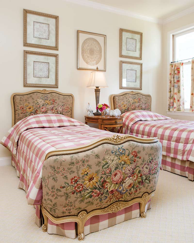 A bedroom with two twin bed frames featuring floral tapestry.