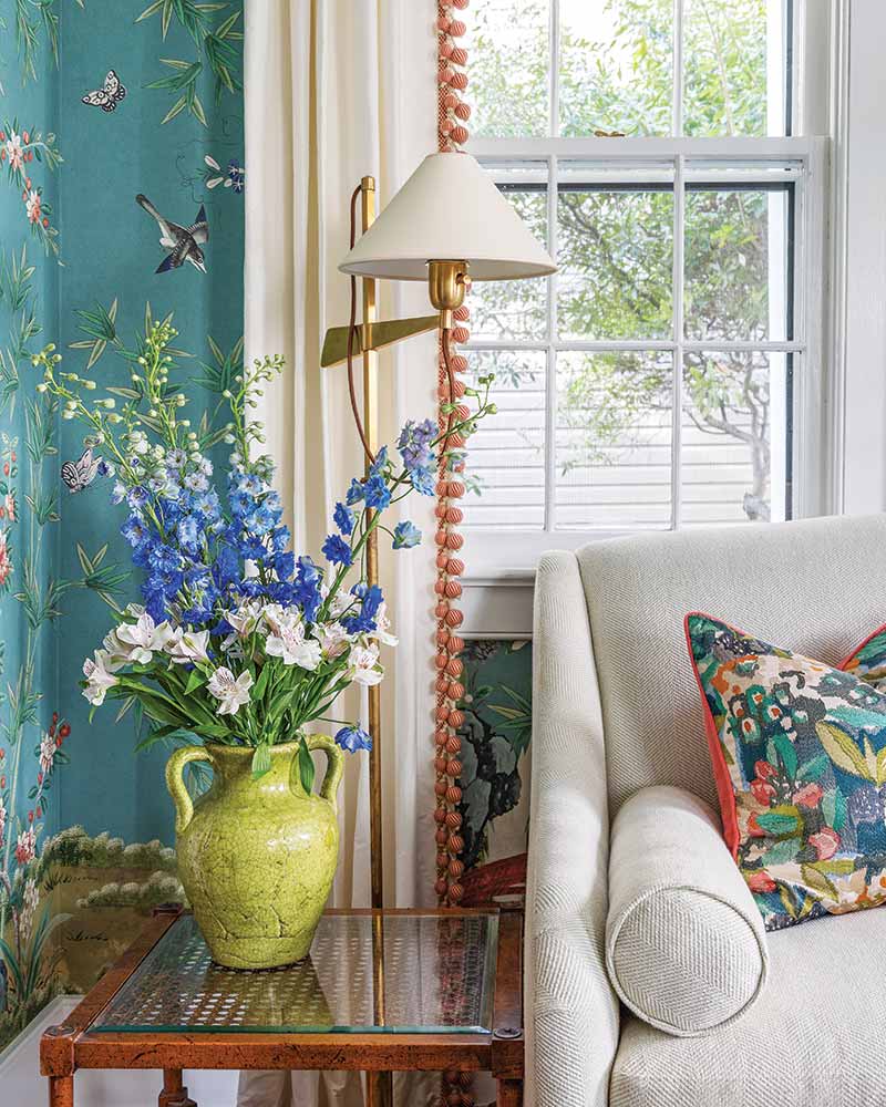 A living room with a teal botanical wallcovering and peach accents.