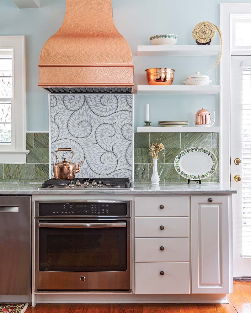 A kitchen with a mosaic tile backsplash behind the range stove.