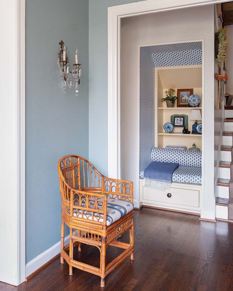 A built-in nook next to the stairs with blue-and-white wallpaper and upholstery. 