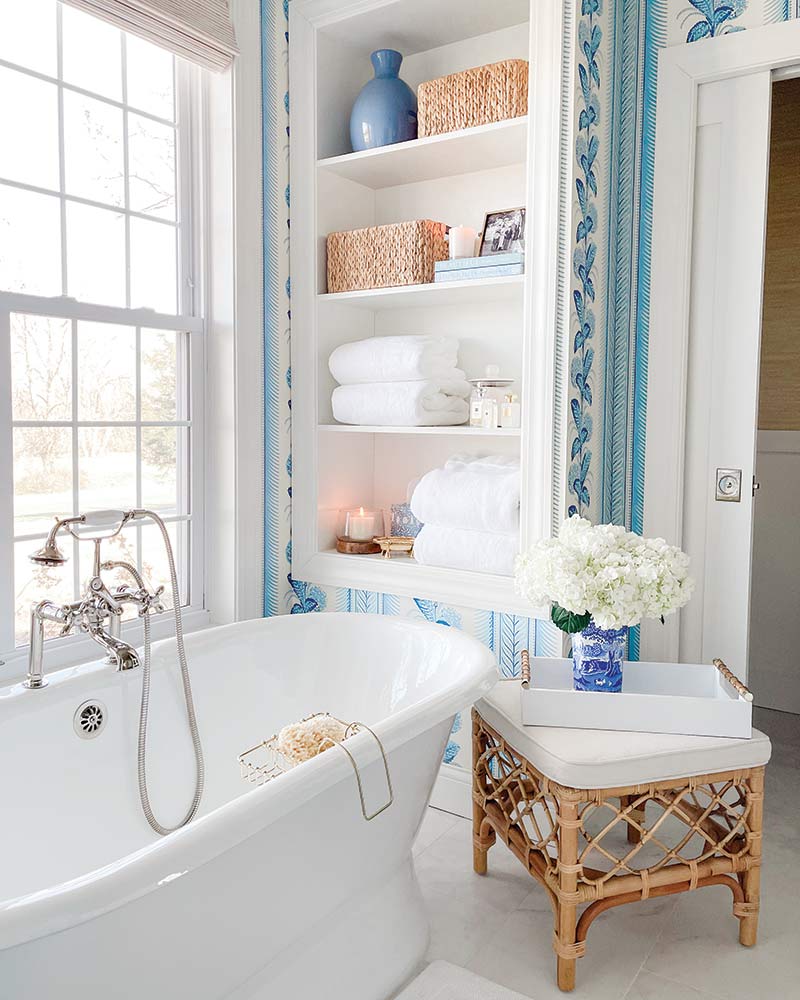 A bathroom with a soaking tub and blue-and-white wallpaper. 