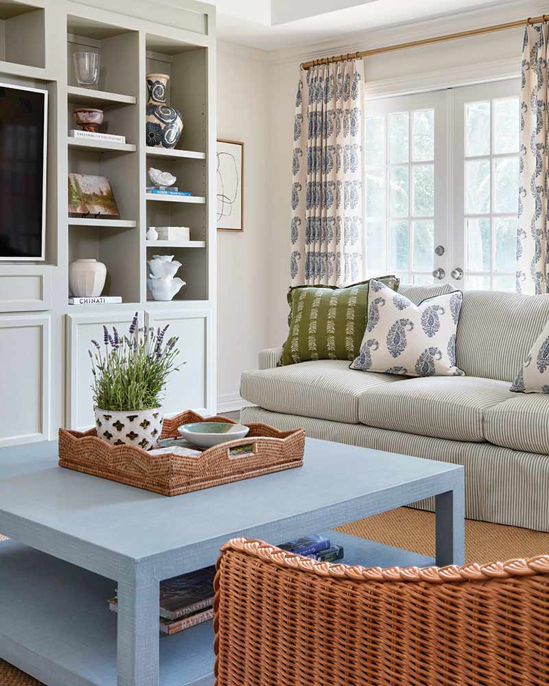 A living room with creamy built-ins, a sky blue coffee table, and printed pillows.