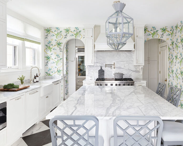 A white kitchen, with gray barstools, and botanical wallpaper.