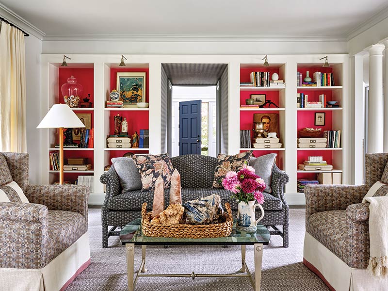 A formal living room with built-ins featuring pink grass cloth wallpaper.