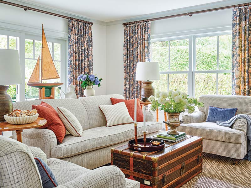 An informal living area with neutral uphostered furnishings, floral drapes, and colorful throw pillows.