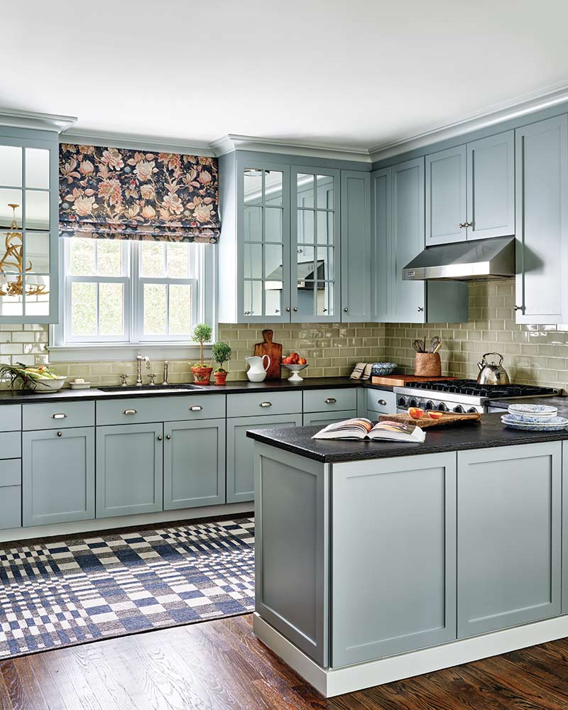 A kitchen with light blue-gray cabinets and black countertops.