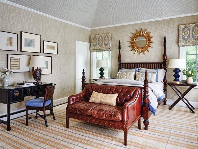 A bedroom with a four poster bed and rich wood and leather tones.