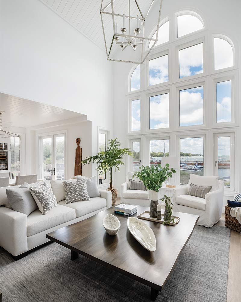 A living room with white furnishings and a large window.