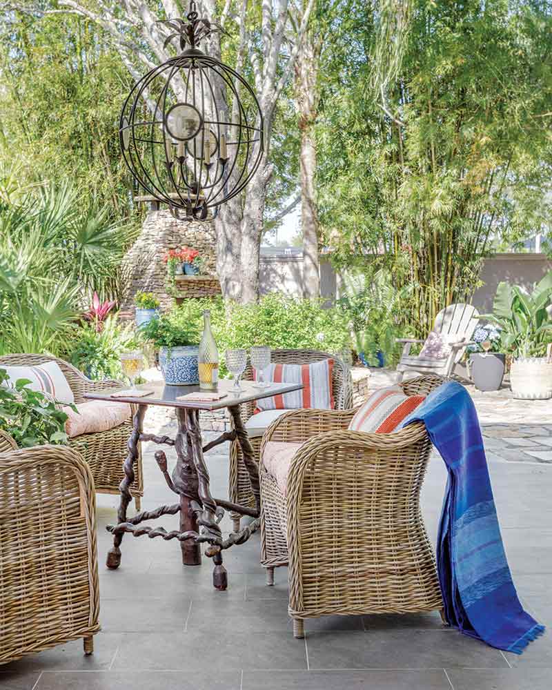 An outdoor dining area with a small table surrounded by rattan chairs.