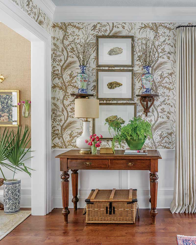A wood console table with a lamp and potted plants. 