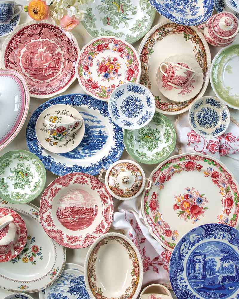 An assortment of colorful transferware plates and cups in various sizes.