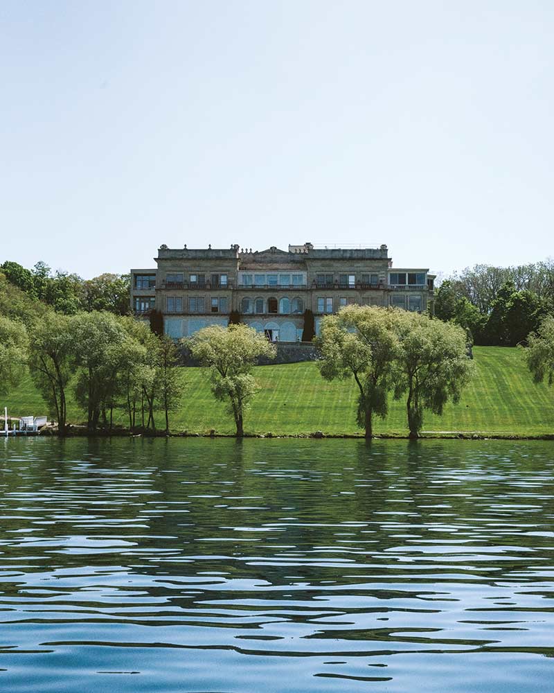 A stately mansion overlooking Wisconsin's Geneva Lake, surrounded by lush green lawns and mature trees.