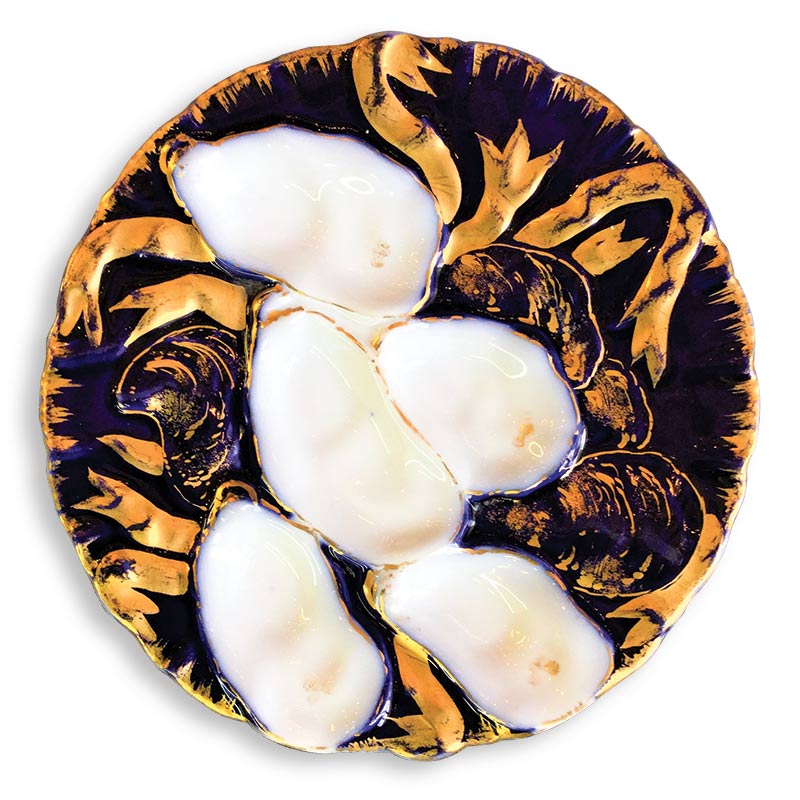 Decorative oyster plate featuring a relief design surrounded by swirling leaf patterns, predominantly in white and golden brown colors.