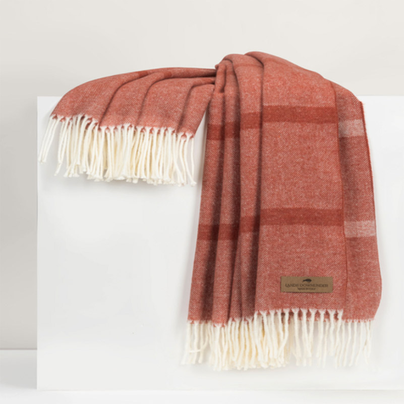 An orange throw with white fringe.