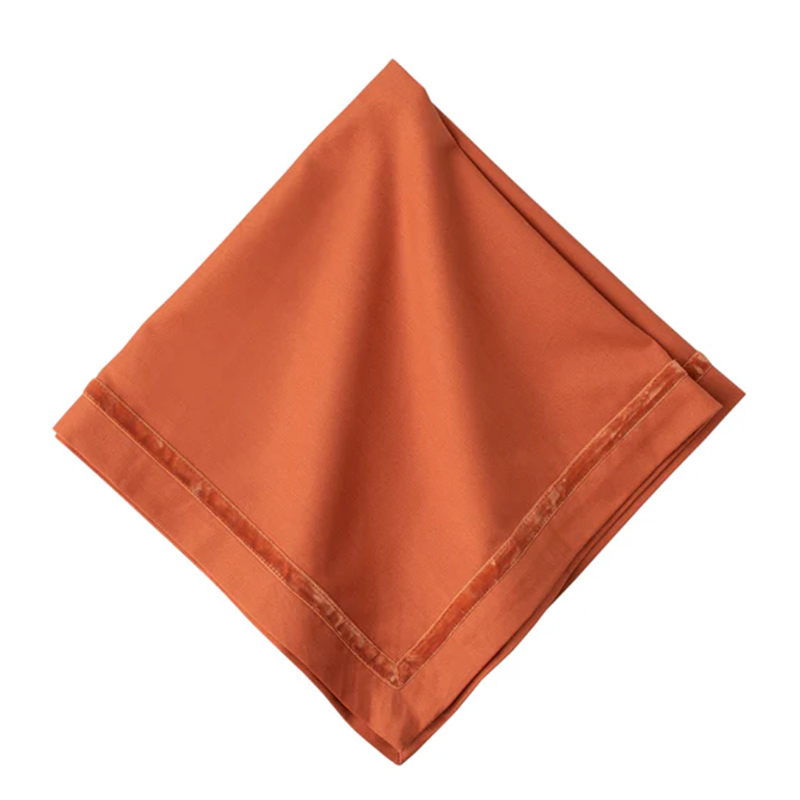 An orange napkin with velvet trim.