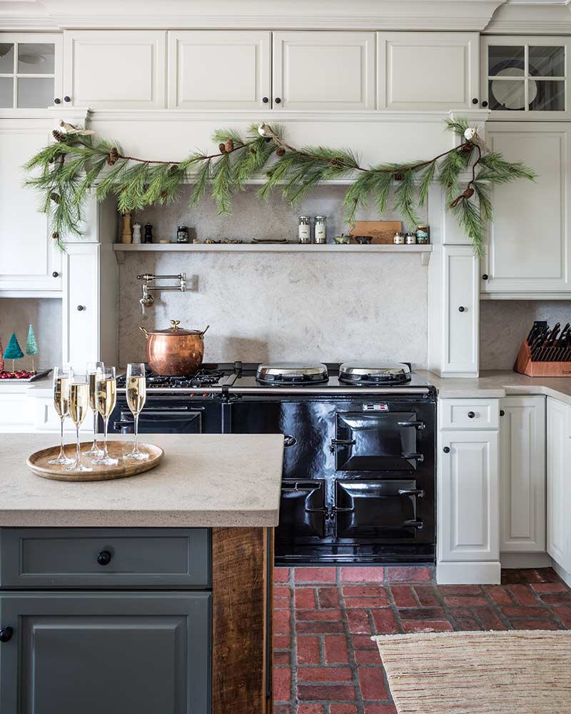 A kitchen with a black cast iron range and an island with glasses of champagne. 