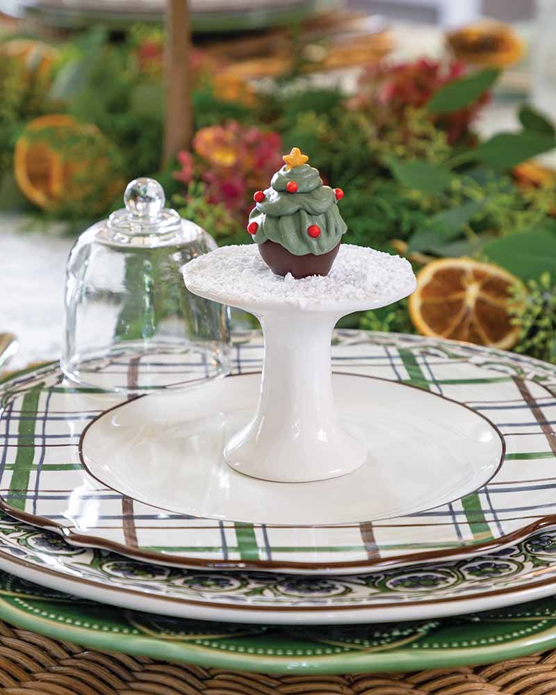 Chocolate candies shaped like Christmas trees are dusted with sugar and covered with small cloches, creating a miniature take on the beloved snow globe.