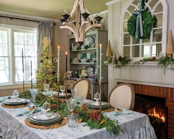 From foraged elements and woodland-inspired tapers to a tree bedecked in simple, rustic decorations, the forest-themed spirit of the room juxtaposes against sleek candlesticks and Louis XVI-style chairs.