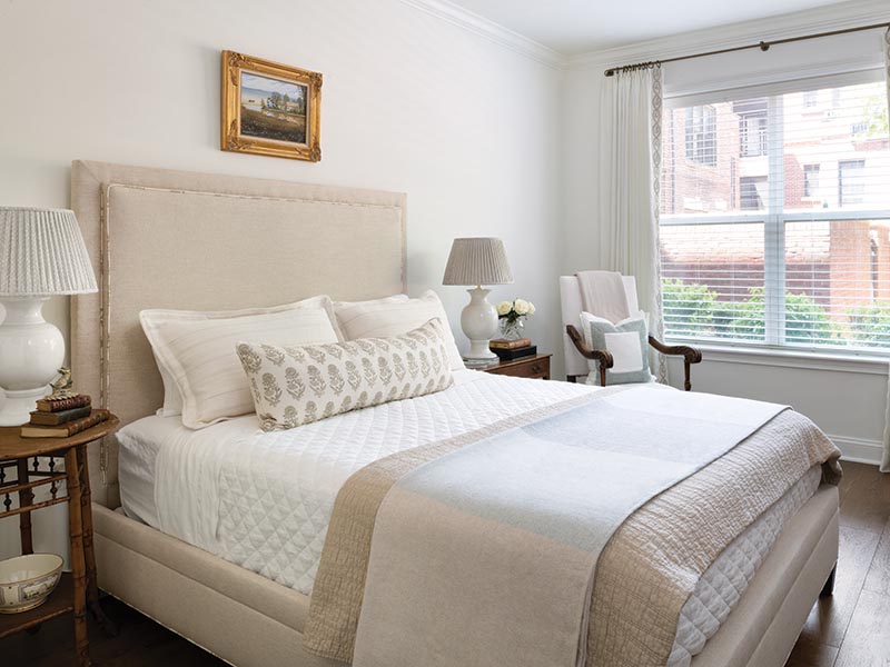 A custom-designed upholstered bed sits front and center in the guest room, accompanied by a desk with an antique bamboo chair