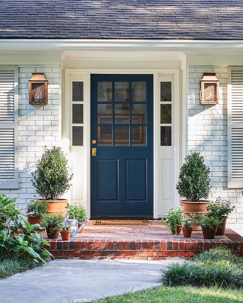 The exterior of the home exudes instant curb appeal thanks to a new nine-lite door painted Farrow & Ball’s Hague Blue that stands out against the painted brick.