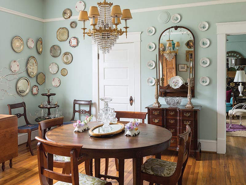 The dining room, where blue once again reigns, houses a number of antique collections, including the Delft bread and butter plates that line the mirror on one wall.