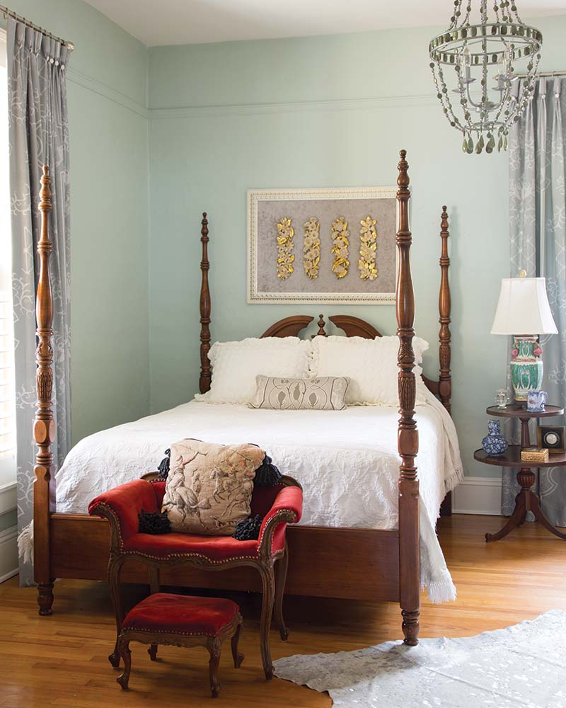 In the front bedroom, a classic four-poster bed and richly hued armchair offer comfortable spots to rest while a more contemporary beaded chandelier hangs overhead.