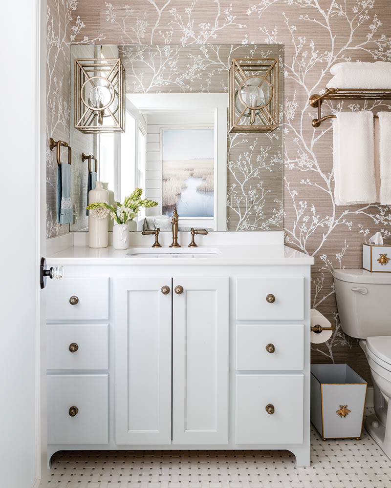 The grass cloth wallpapered bathroom, with its glassed-in shower and integrated mirrored sconces, exudes a spa-like feel.