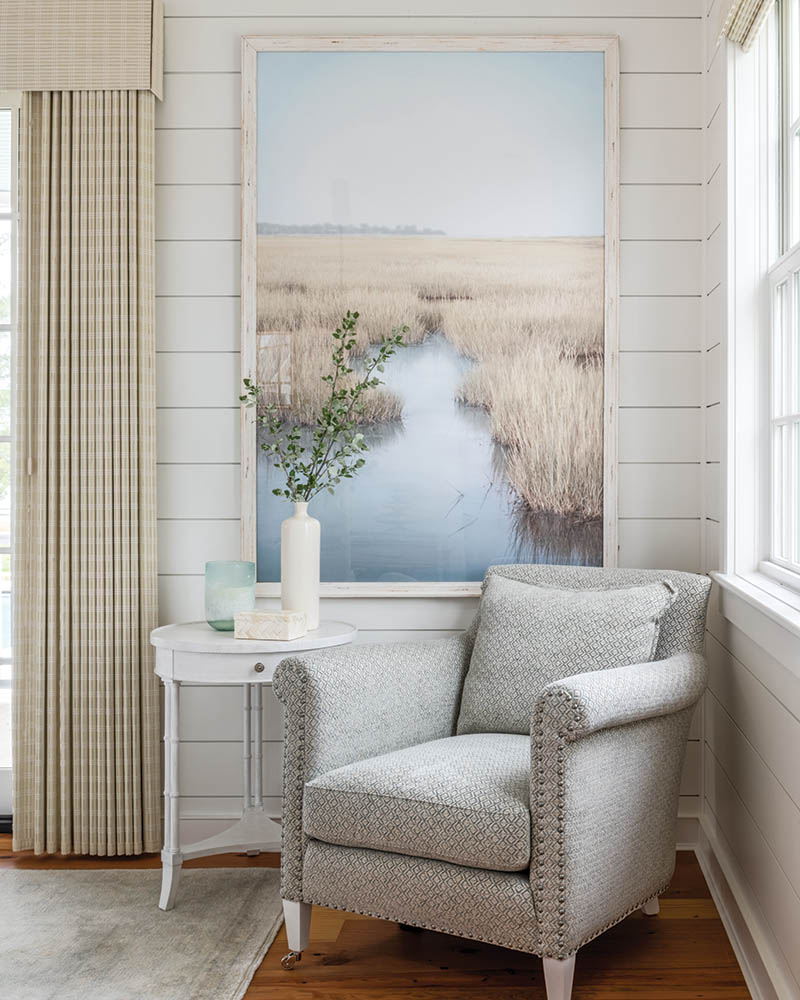 In the bedroom, an overscale framed photograph of tidewater marshes is tucked into an armchair nook. This artwork, reminiscent of the exterior, inspired the space’s palette and mood.