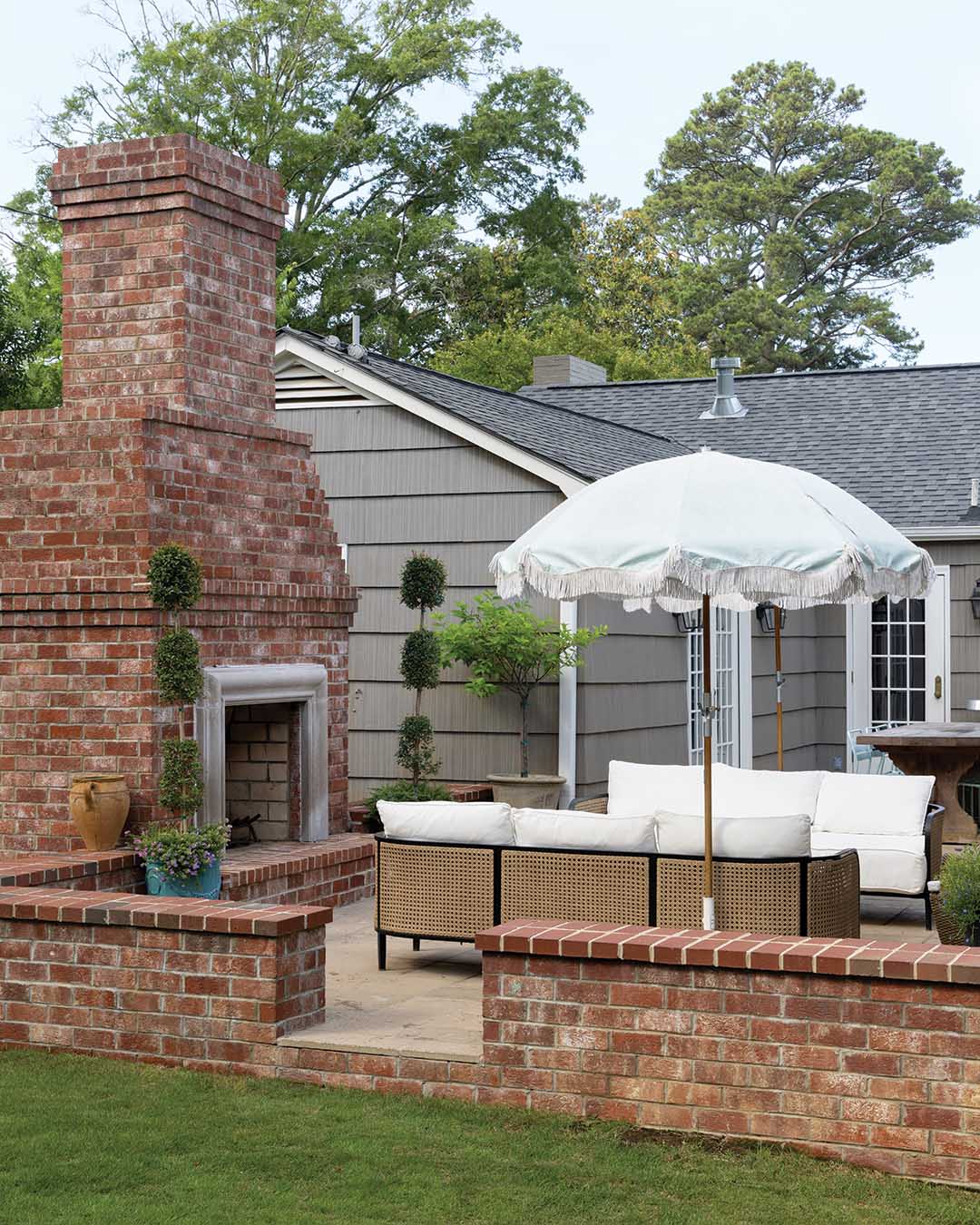 Arranged around a cypress table built by her dad, green bistro chairs mimic those famously found around Paris, and a brick fireplace serves as the anchor to an alfresco living room, complete with umbrellas to provide shade in the warmer months.