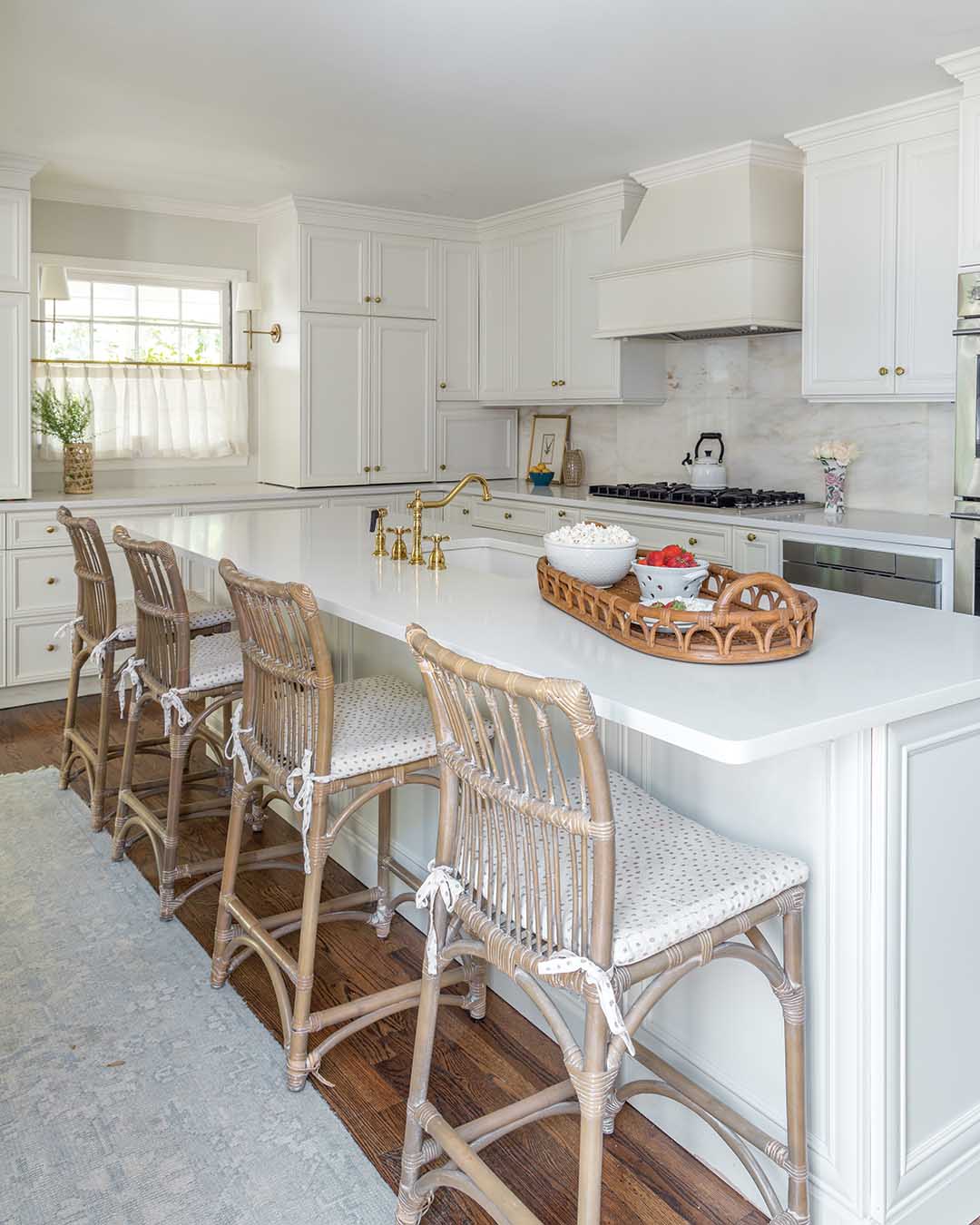 Made from Alabama white marble, the tile of the backsplash was cut from tabletops salvaged from a local American Legion Post, and the café curtain on the window disguises the view of the carport without blocking the natural light.