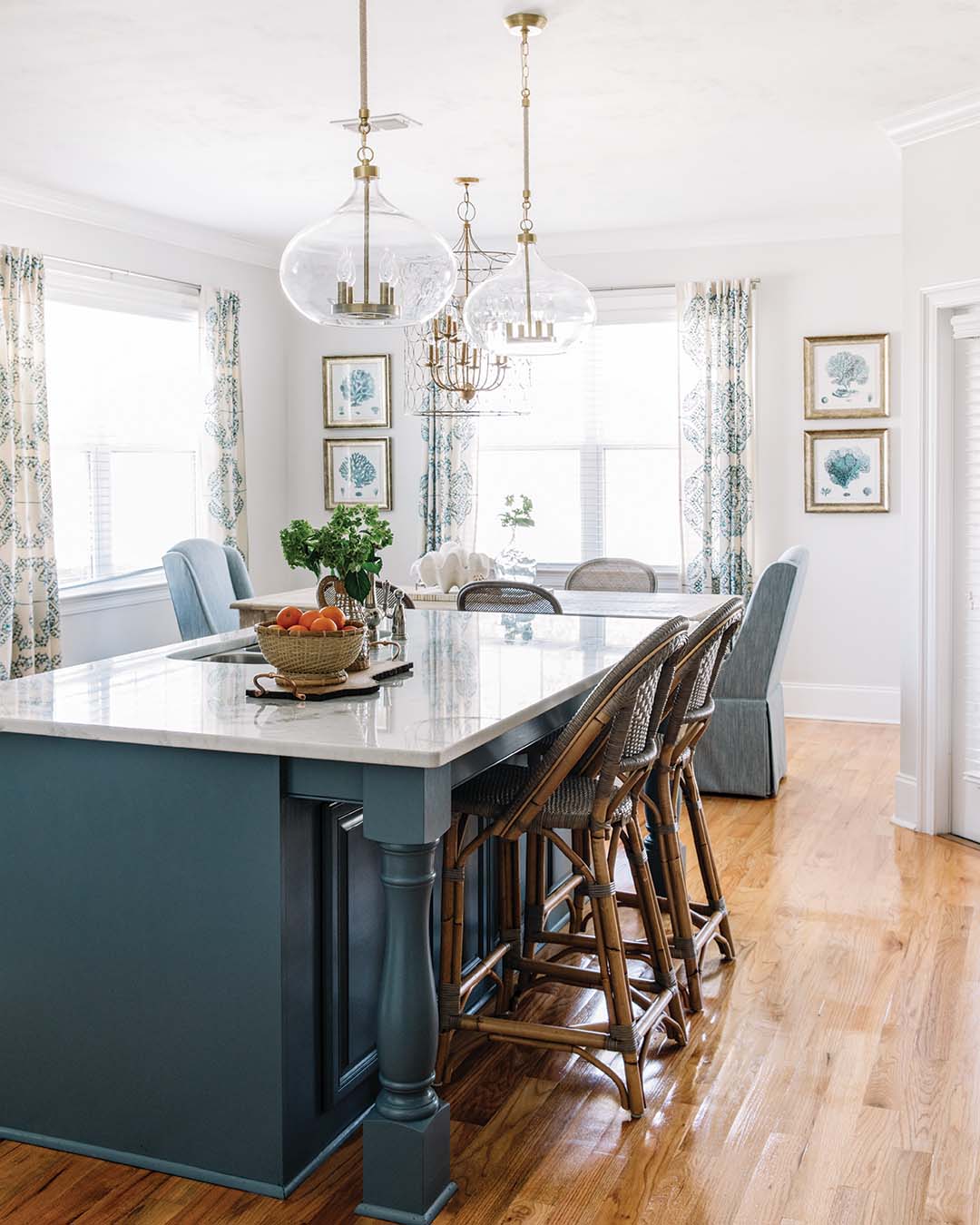 The kitchen received a refresh in the form of a cosmetic facelift. Jessica and her clients chose to repurpose the cabinetry with paint but selected new countertops, backsplash, and lighting. Blue accents add aquatic interest to the dolomite counters while also complementing the grand island’s splashy color.