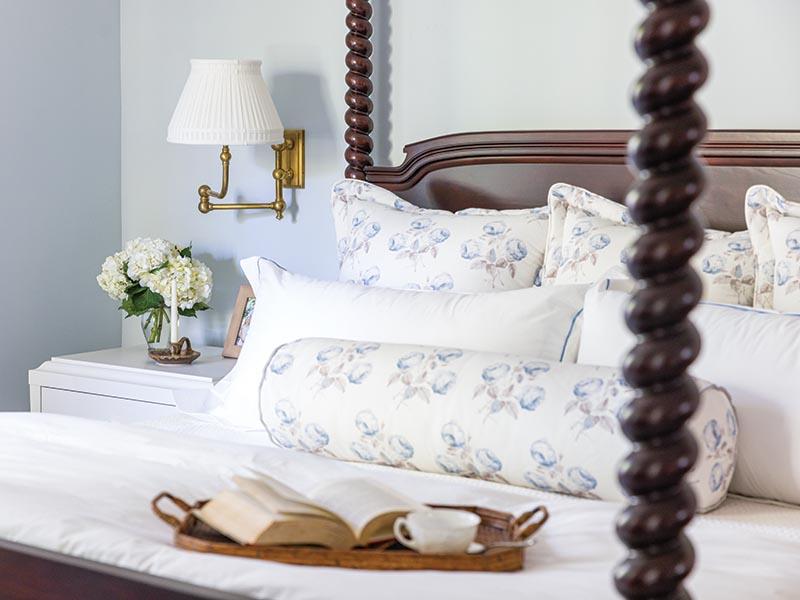 Upstairs, the primary bedroom embraces a soft and soothing palette with pattern limited to the euro and bolster pillows.
