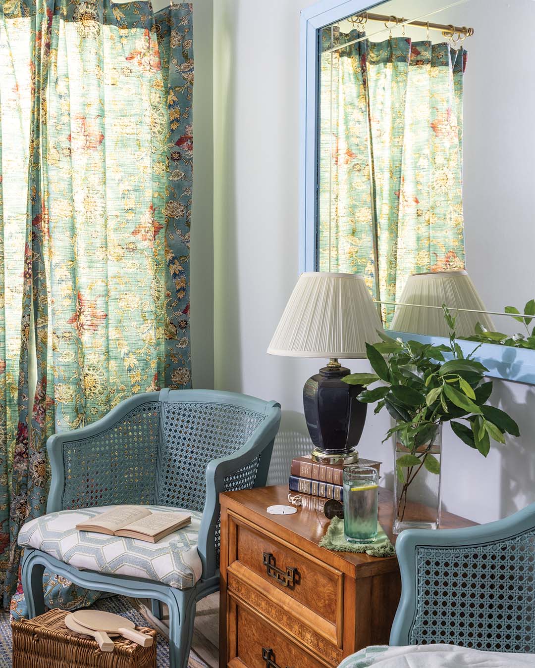 A duo of cane chairs painted aqua blue flanks a small end table for a peaceful reading corner.