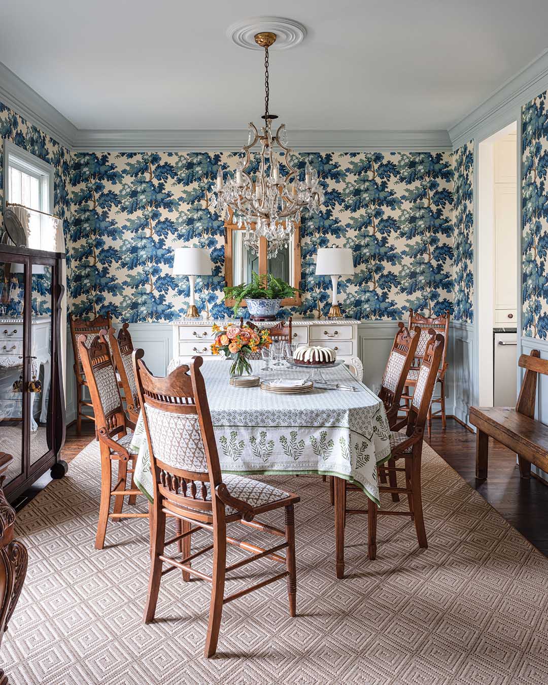 To the left of the entry, a once unassuming dining area now commands attention thanks to the striking wallpaper by The House of Scalamandré and the painted ceiling, trim, and paneling beneath the chair rail.