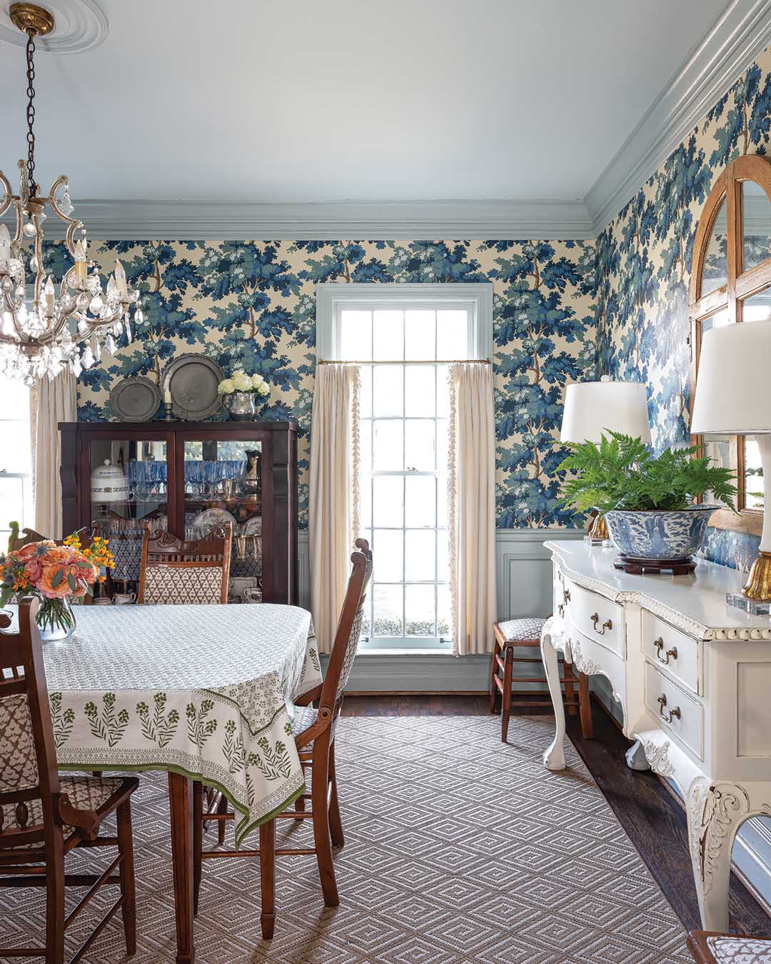 Anna and her client opted for sill-length window treatments in the dining room. “It’s old-fashioned, but in this setting, it’s really great,” Anna says, adding that their decision for a shorter length was influenced in part by the family’s Maltese dog, Buster. “This [room] looks out to the front of the house, and their Maltese is constantly perched in that front window, so we made the drapes sill-length for him.” The white sideboard is old but was purchased new to the homeowners. Anna says they needed something painted to break up the brown furniture in the space. “We found that [piece] at an antiques store in Nashville and just thought it looked perfect there,” she says.