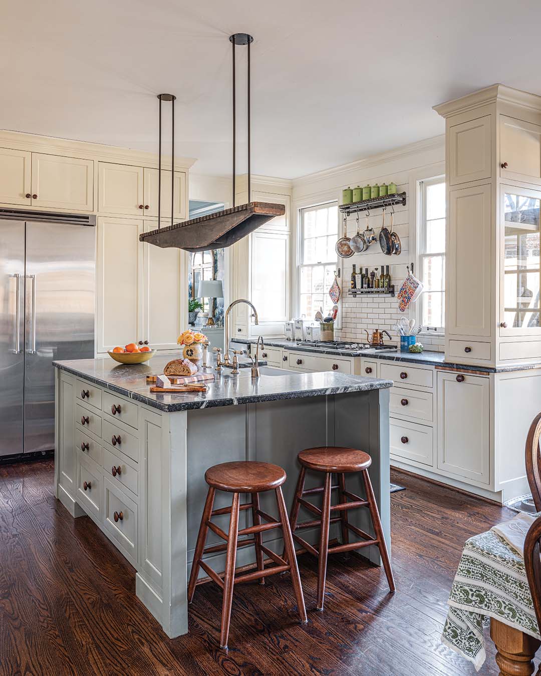 The chunky cabinet knobs and shiplap detail above the subway tile over the cooktop add a touch of farmhouse flair to this custom kitchen.