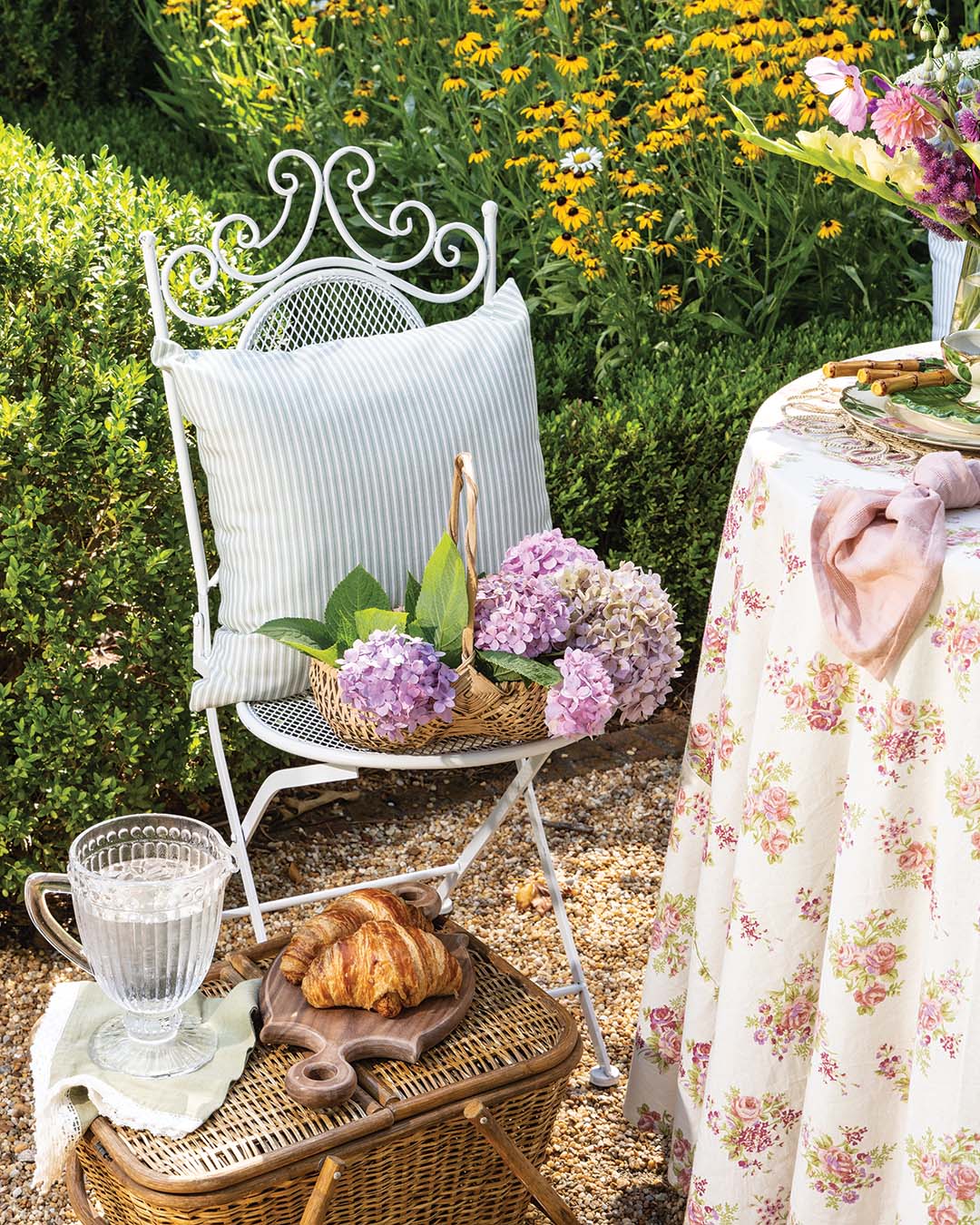 A romantic floral tablecloth and dishware adorned with a soft blossoming pattern reflect the tranquility and natural beauty of a lush country garden.