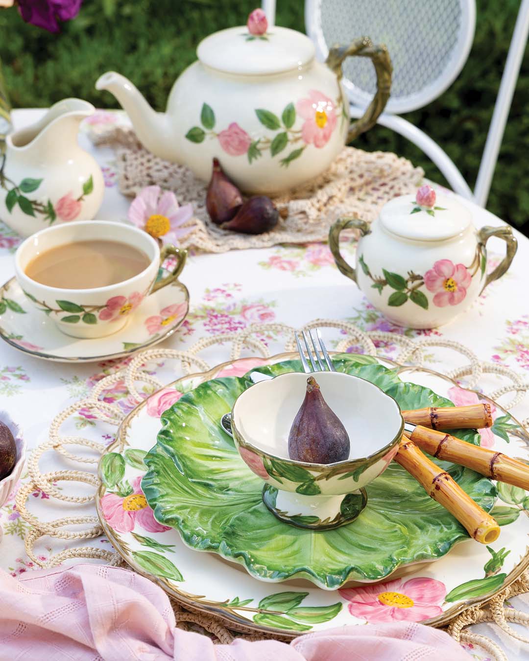 Atop woven wicker place mats, delicate pink napkins add a touch of gentle sophistication, mirroring the petals dispersed throughout the garden. Cabbage-inspired dishware and bamboo flatware offer contrast to the table setting, encouraging guests to slow down and reconnect with the earth’s bounty.