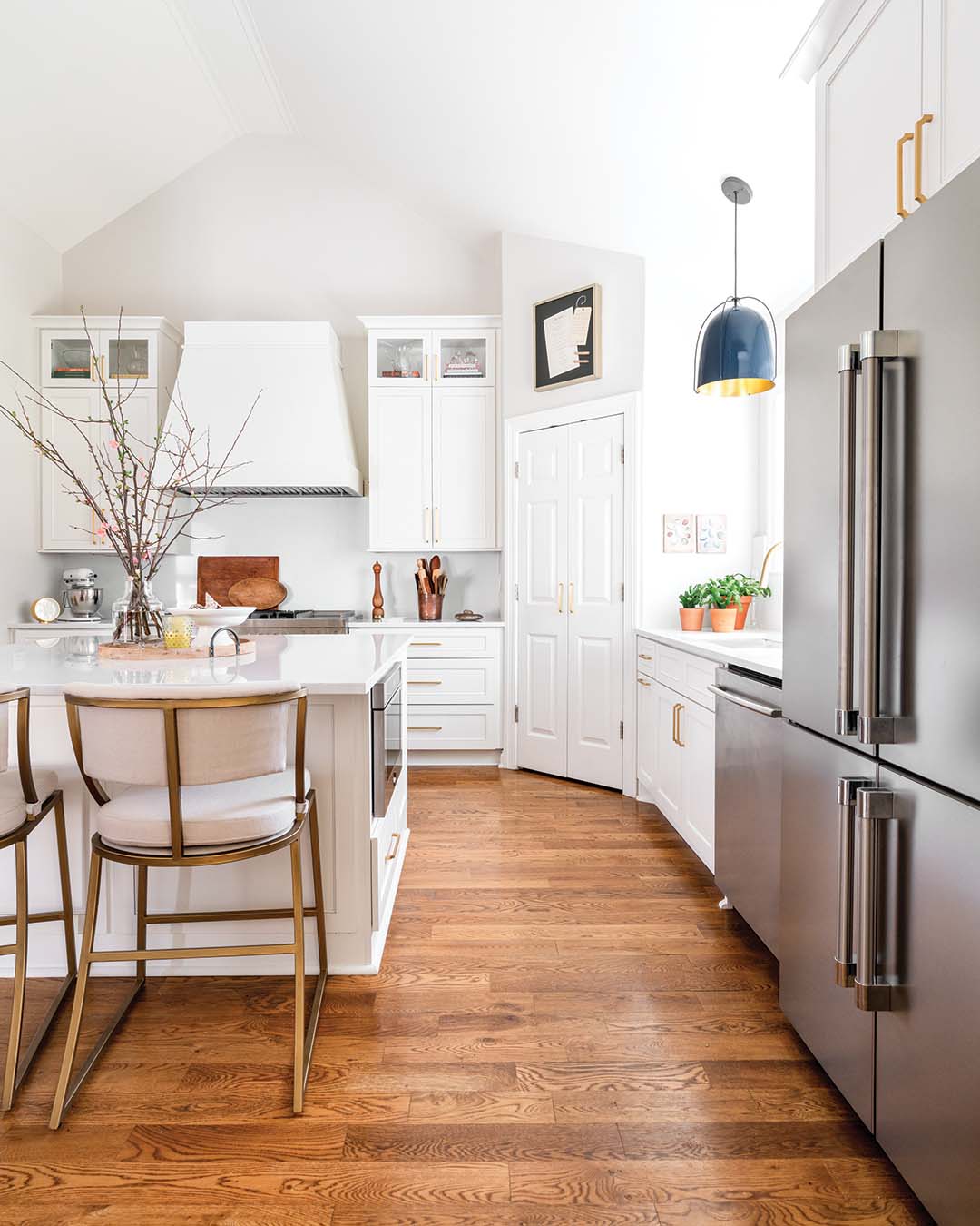 And while a crisp and clean white kitchen, updated and equipped for an avid cook, was a top priority for Frannie, the design team also infused the open-concept space with points of interest, like decorative molding, sleek brass hardware, and a unique pendant light, to coalesce with the colorful den.