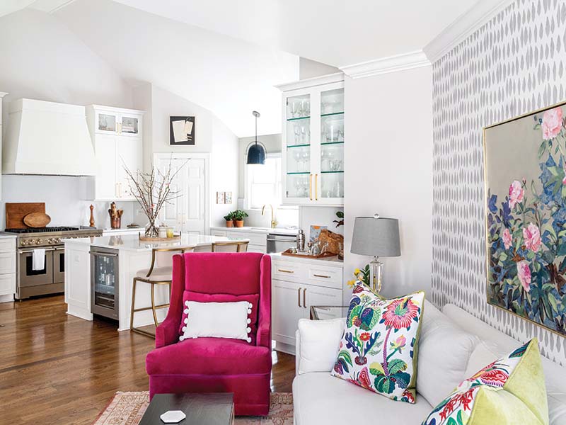 A spirited ambience unfolds in this area, where an accent wallpaper and a bright fuchsia armchair keep company with animated floral fabrics and artwork by Frannie’s mom.