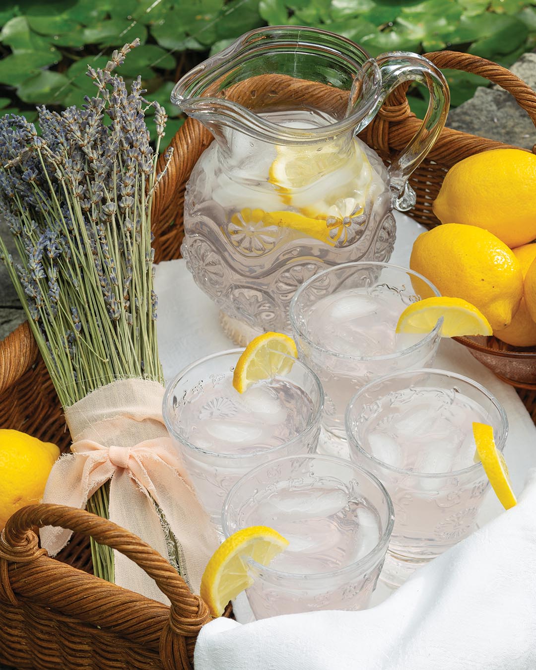 A glass water pitcher embellished with zesty lemon slices offers a refreshing detail to the setting. A bundle of delicate lavender invokes the charming essence of the French countryside.