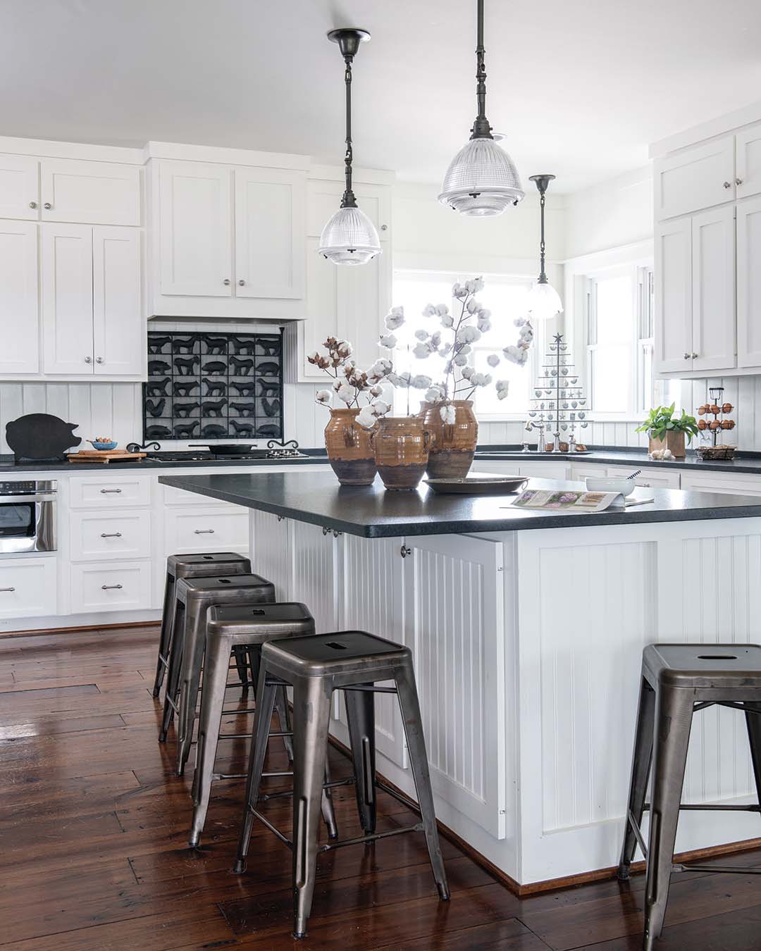 In the kitchen, the shiplap hangs vertically, and an oversize island separates the workspace from the gathering spaces. A fire screen backs the range and features animal figures, a nod to the farm itself.