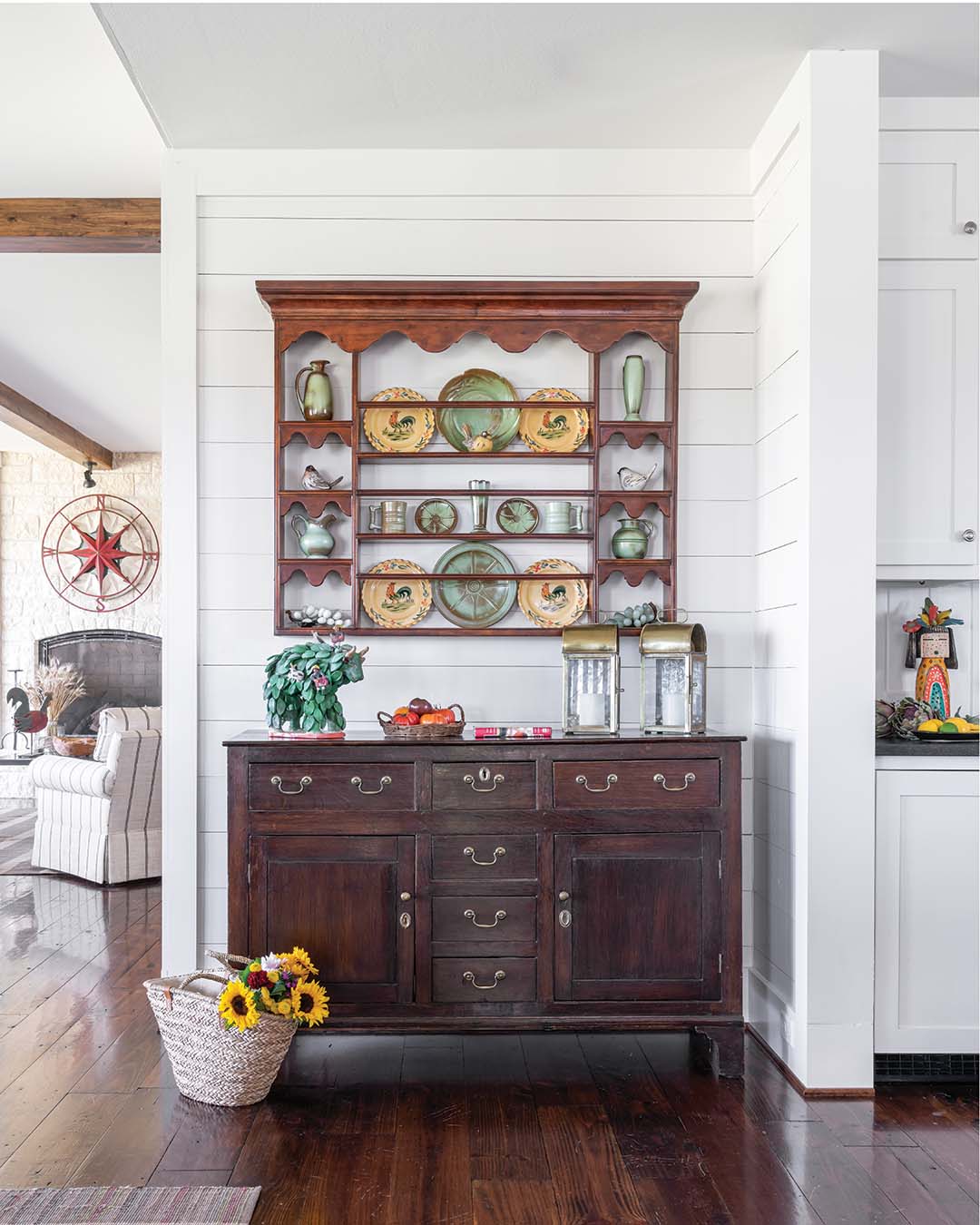 The rich patinas and warm woods of the antique pieces stand out against the stark white shiplap on the walls.