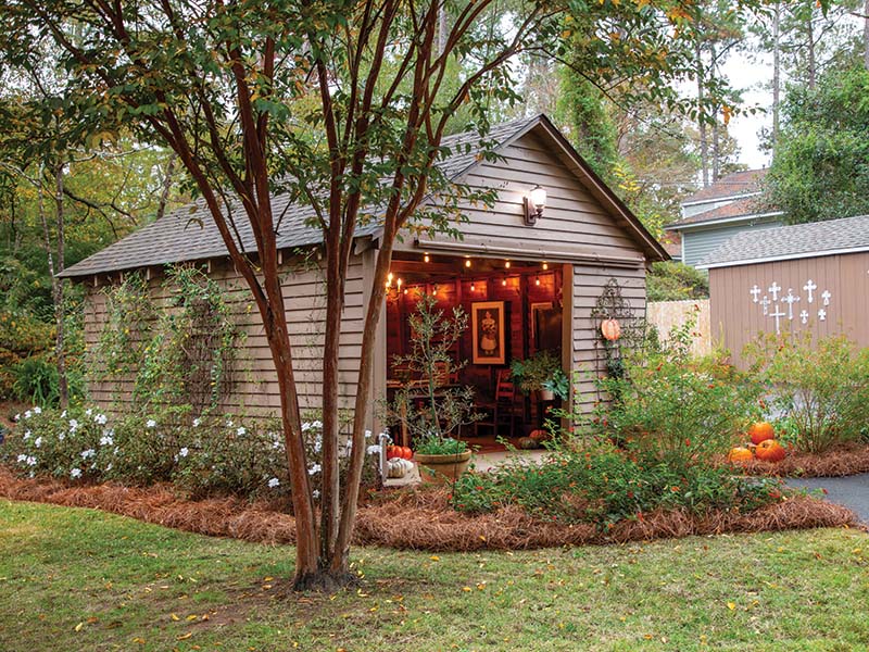 During breezy autumn evenings, string lights and taper candles lend a welcoming glow to the outdoor dining space Beth filled with secondhand finds.