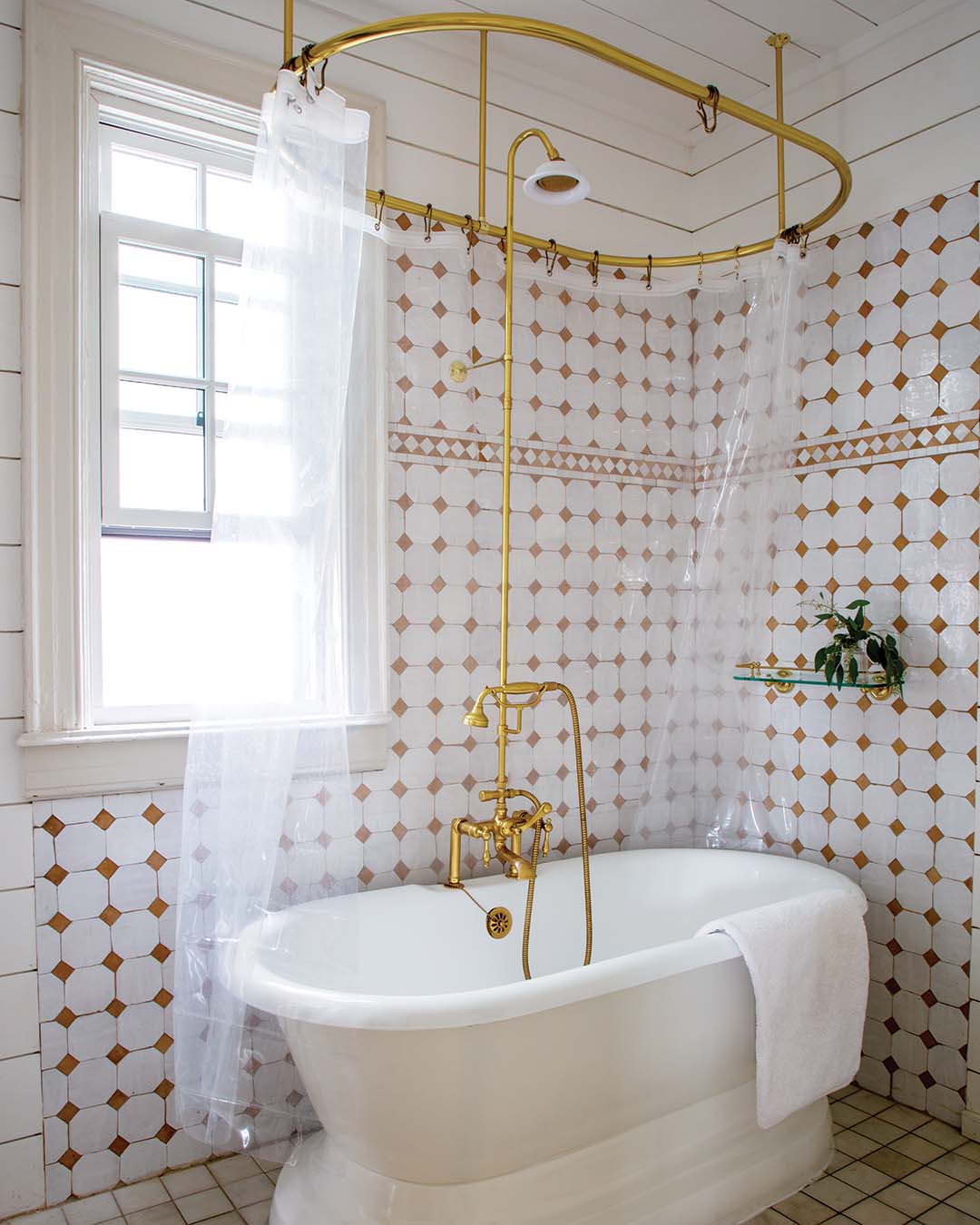 The bathroom features terra-cotta tile created in collaboration between Zio & Sons and clé. Paired with wood floors painted a glossy white, the rich but airy backdrop perfectly shows off a curated collection of antique pieces.