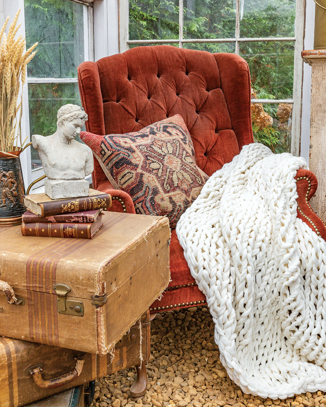 Feeding into that spirit are the antiques that she incorporated into the space, which include an apothecary cabinet turned buffet that charms with its cracked paint patina. Collected favorites such as antique busts and leather-bound books fill empty surfaces, tucked in among sprigs and twigs clipped from the property, combining the cozy atmosphere of a book-filled study with the richness of an autumn garden.